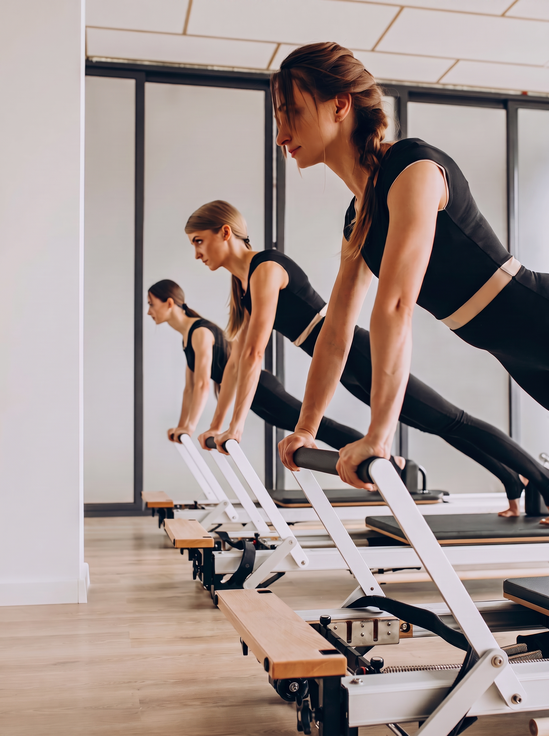 Pratiquantes en cours collectif de Pilates sur reformers dans un studio lumineux